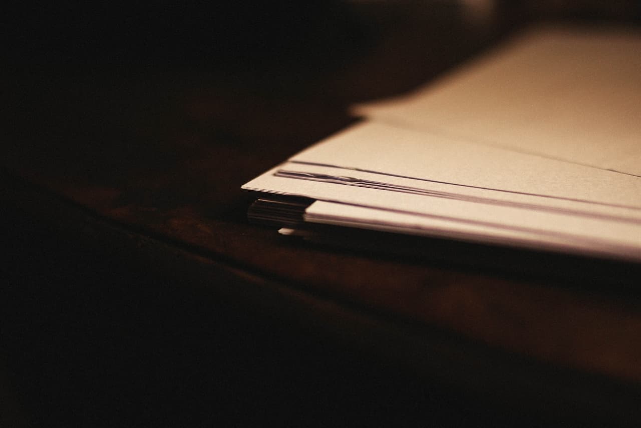 A stack of blank paper and a pen on a bare desk